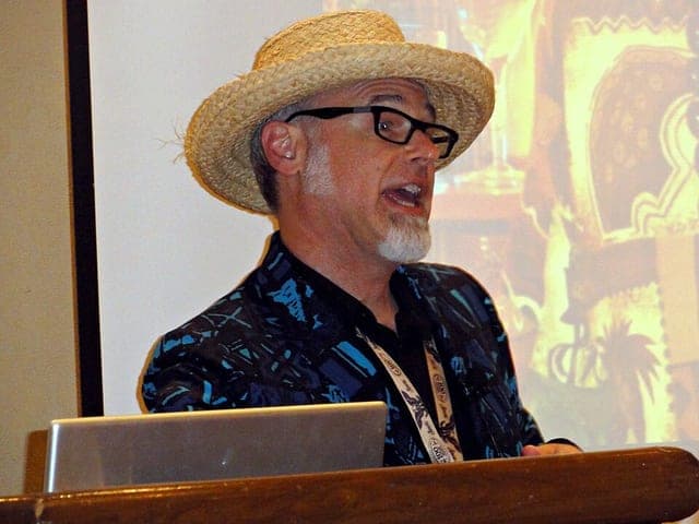 Photograph of drink historian Jeff “Beachbum” Berry speaking at a lectern in a straw hat.